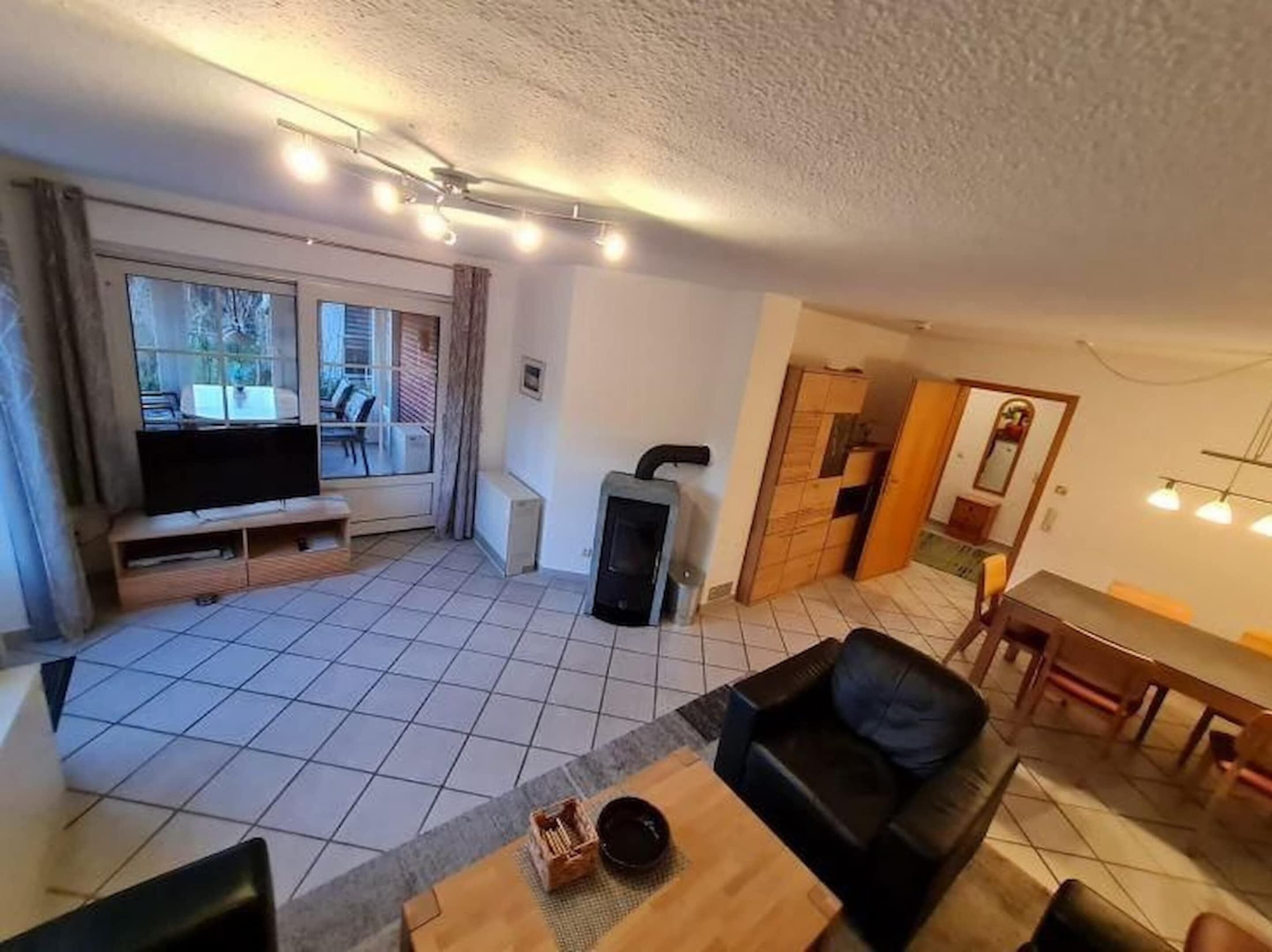 Een woonkamer met een televisie, bank en een eethoek.
