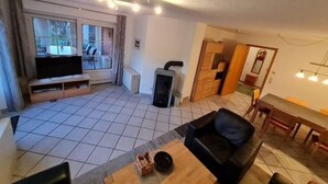 Una sala de estar con televisor, sofá y comedor.