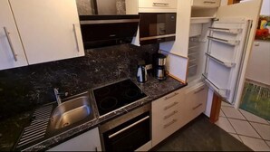 Una cocina moderna con encimera negra, electrodomésticos de acero inoxidable y muebles de cocina blancos.