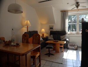 Ein Wohnzimmer mit Esstisch, Stühlen, einer Couch und einem Deckenventilator.