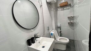 A modern bathroom with a white sink, toilet, and shower. - Era Hong Mai Apartment (Hanoi)