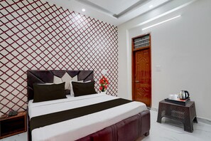 Habitación de hotel con cama, mesita de noche, puerta de madera y una pequeña mesa con bandeja.