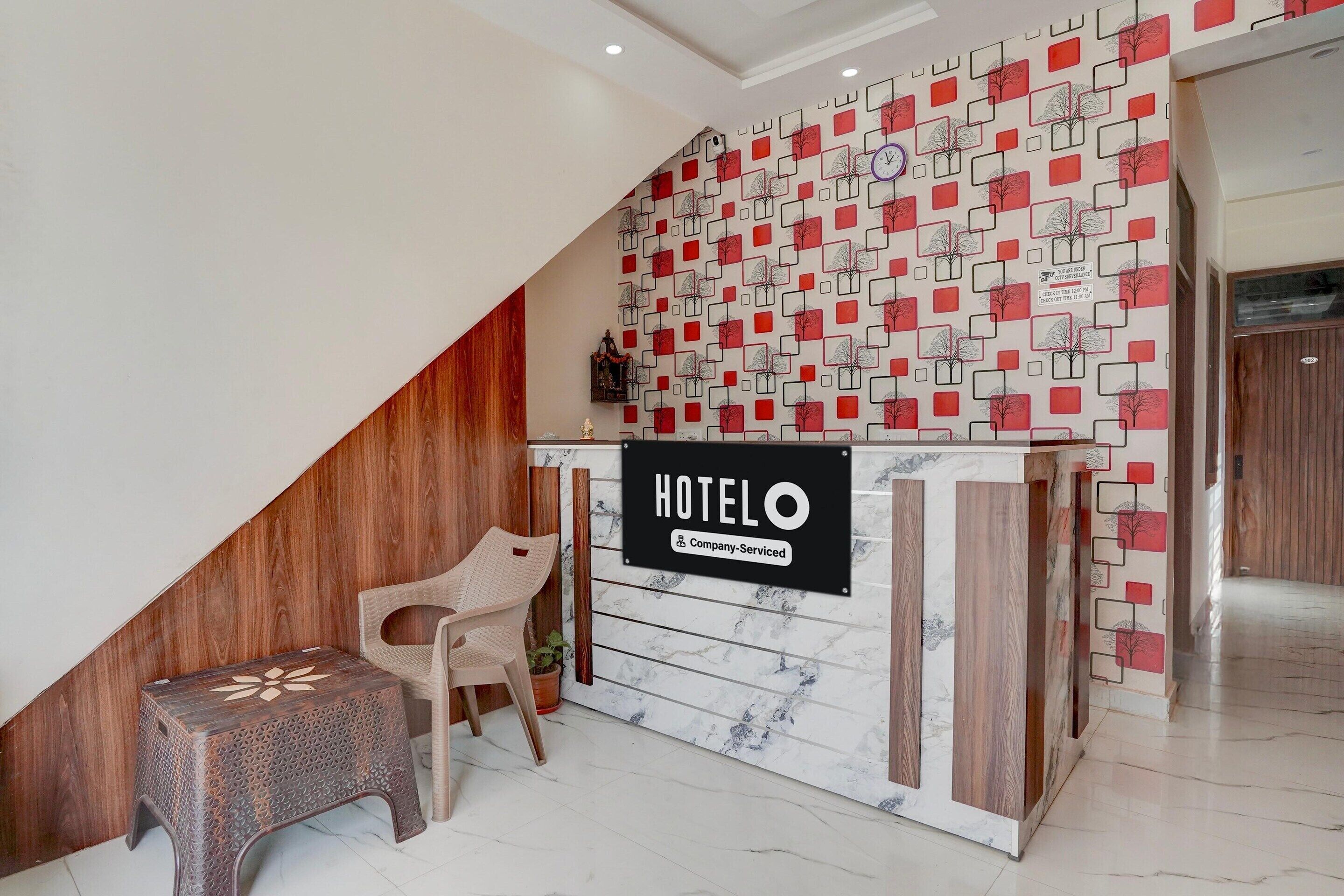 A hotel reception desk with a sign, a wooden sloped ceiling, and a patterned wall.