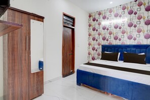 A bedroom with a bed, a wardrobe, a door, and a wall with a leaf pattern. - Saver Double Hotel O Isbt Holiday Spot (Mohali)