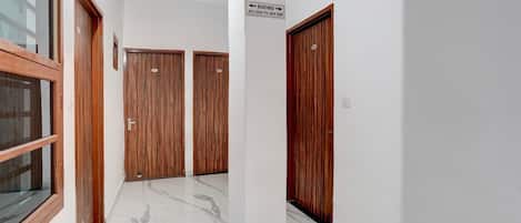 A hallway with wooden doors, a 'No Smoking' sign, and a directional sign for rooms.