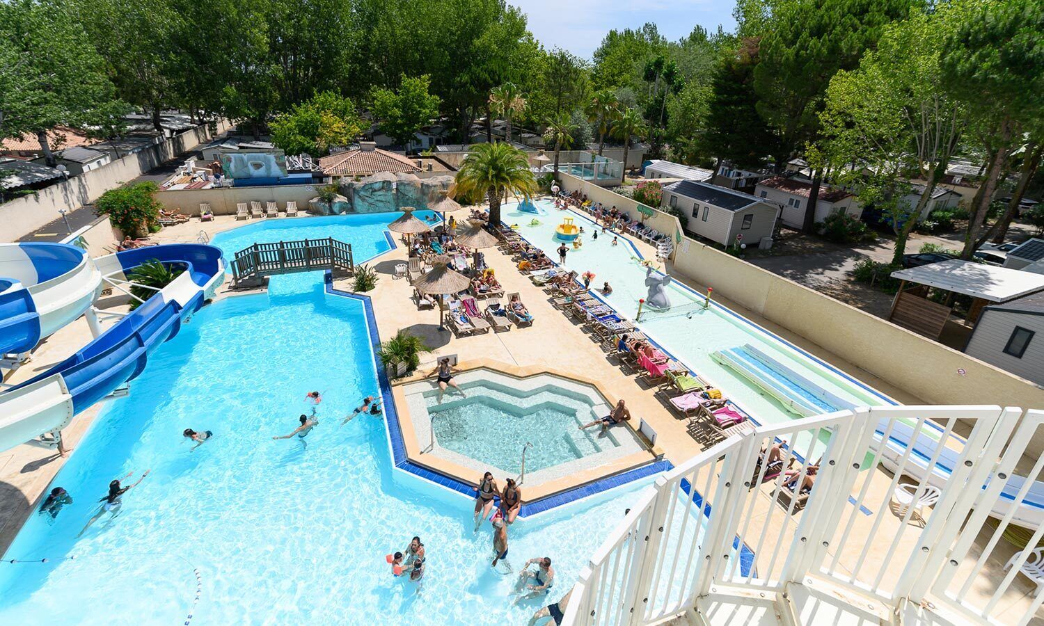 Une grande piscine extérieure dotée de plusieurs toboggans et d’un espace distinct avec un bain à remous.