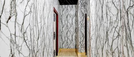 A hallway with marble walls and a tiled floor.