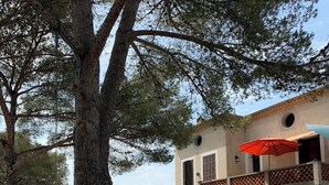 Un bâtiment à la façade en pierre, doté d’un balcon et surmonté d’un parasol rouge.
