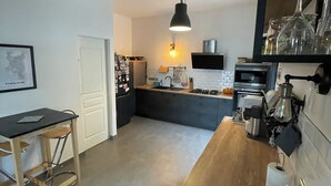Une cuisine moderne dotée d’un îlot central, d’un luminaire suspendu et d’un mur d’accent en briques.