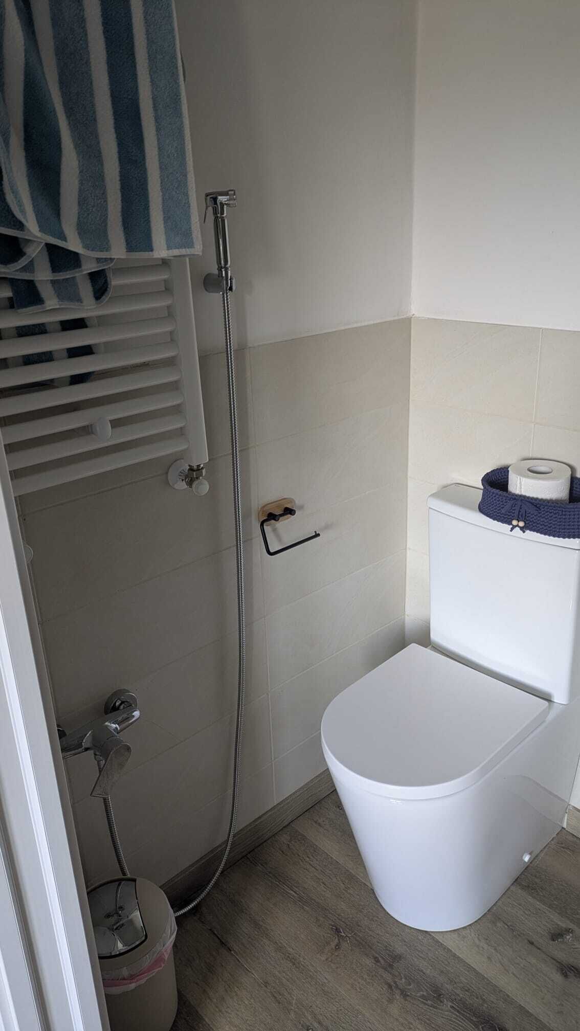 Un baño pequeño con ducha, inodoro y barra para toallas.