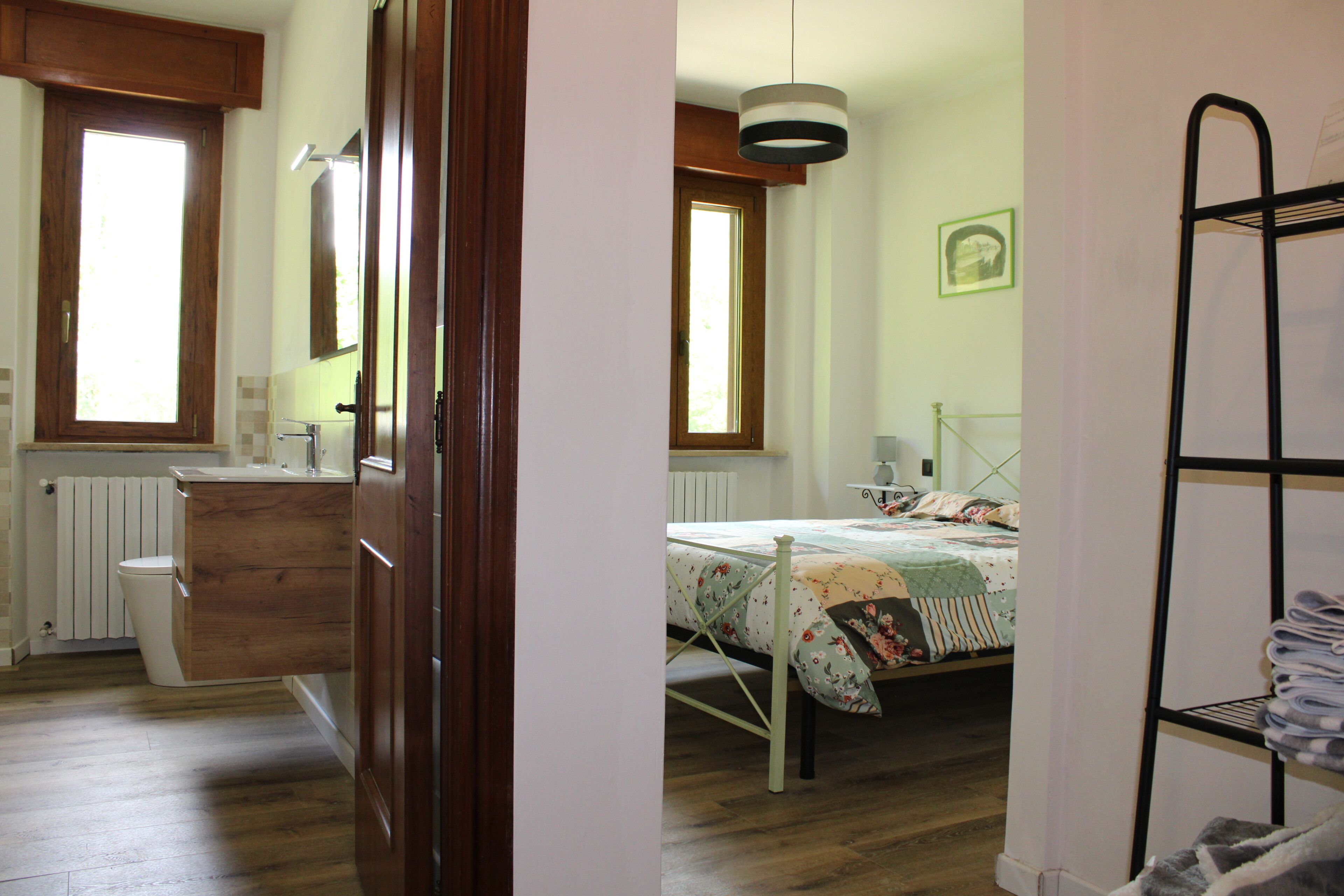 Un dormitorio con una cama de madera, una mesita de noche, un radiador, una ventana y una cama litera.