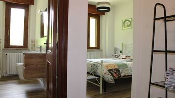 Un dormitorio con una cama de madera, una mesita de noche, un radiador, una ventana y una cama litera.