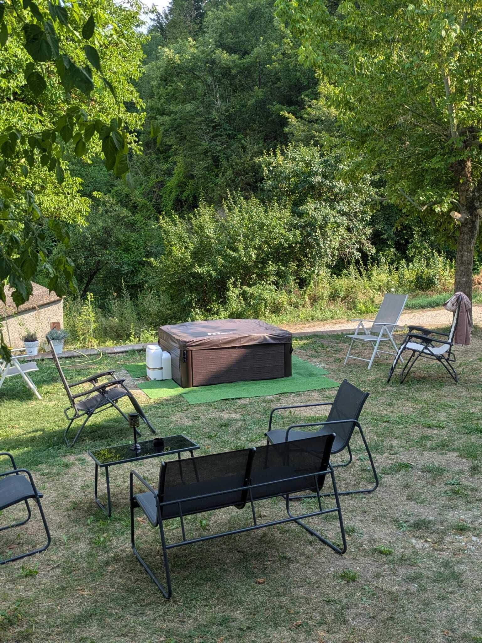 An outdoor seating area with a covered fire pit, lounge chairs, and a small table.