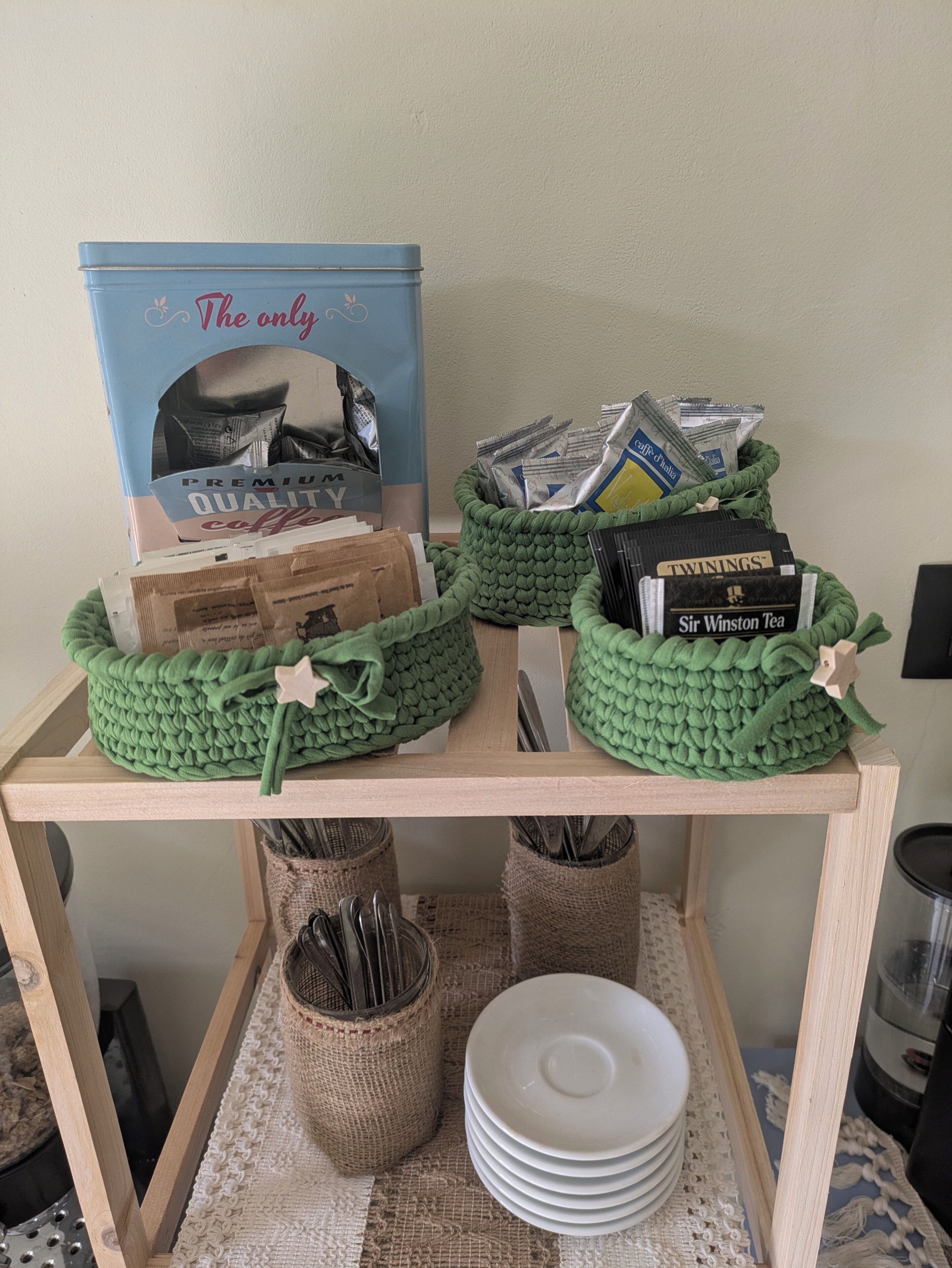 Una mesa de madera con dos cestas verdes que contienen infusiones y una caja con la etiqueta 'The only PREMIUM QUALITY coffee'.