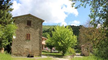 Un bâtiment en pierre doté d’une fenêtre et d’une porte, entouré de verdure et sous un ciel dégagé.
