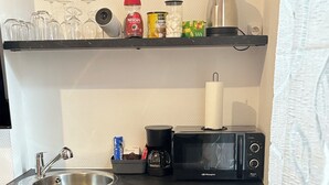 Pieni, käytännöllinen keittiönurkkaus, jossa on pesuallas, kahvinkeitin, mikroaaltouuni ja pieni jääkaappi.