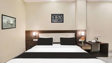 A hotel room with a bed, bedside tables, a nightstand, a vase with flowers, and wall art.