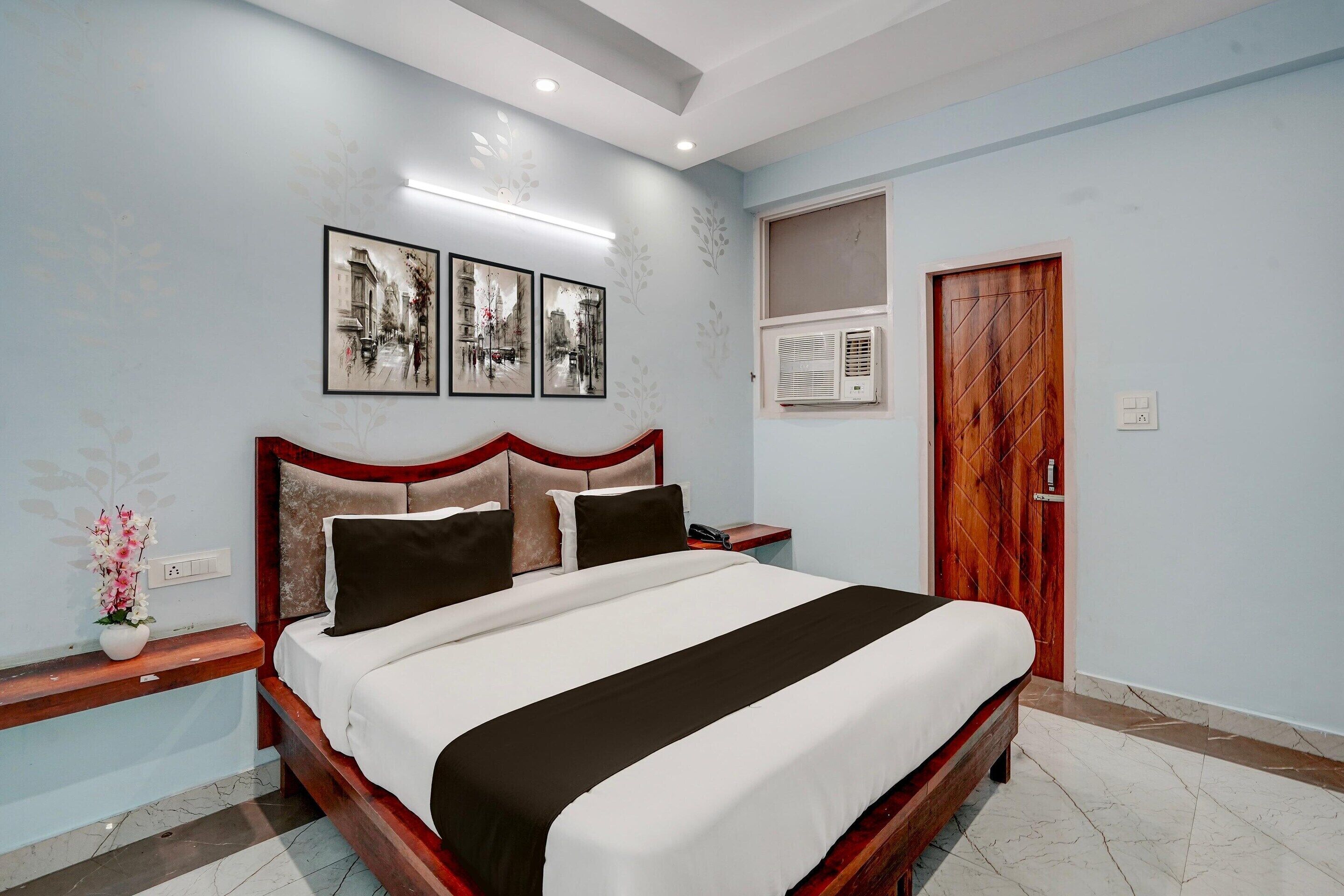 A bedroom with a bed, nightstand, wall-mounted air conditioning, and a door.