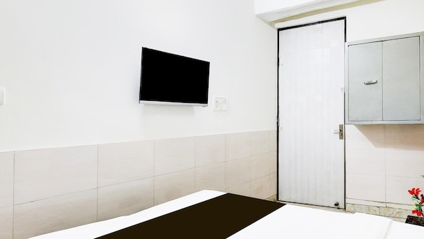 Ein Hotelzimmer mit Bett, Wandfernseher, Tür und Schrank.