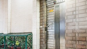 Eine Metalttür mit einem Schild, eine Ziegelwand und grüne Pflanzkäfige.