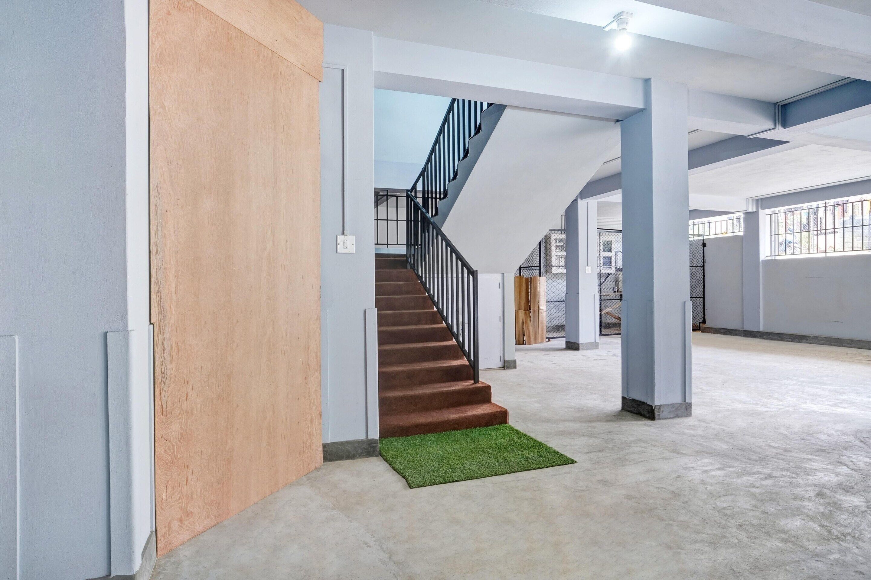 A spacious interior with a staircase leading to upper levels, concrete flooring, and a wooden accent wall.