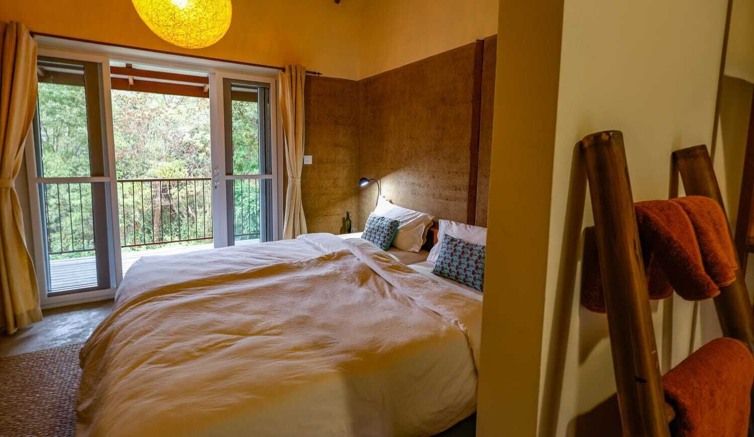 Un dormitorio con una cama grande, una ventana con cortinas, un cabecero de madera y una mesita de noche con lámpara.