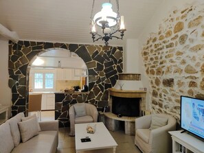 Ein Wohnzimmer mit Steinwand, Kamin, Fernseher und Sofa.