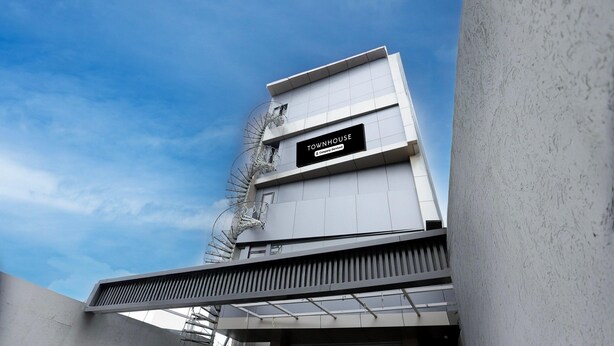A modern building with a sign reading 'TOWNHOUSE' and a covered entrance.
