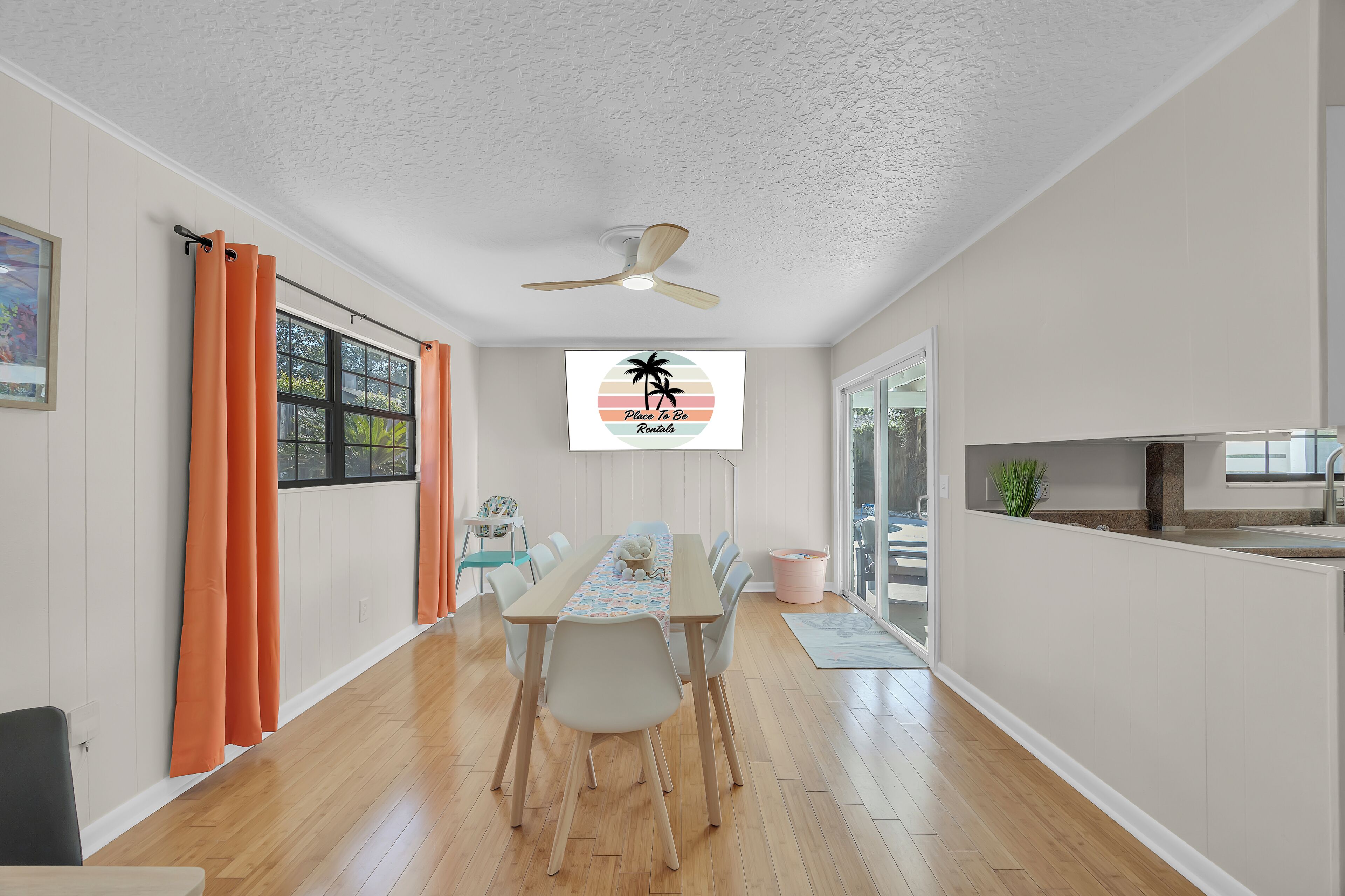 A dining area with a table, chairs, a ceiling fan, and a view of the outdoors.