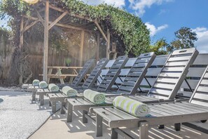 A row of sun loungers with towels, a wooden pergola, and a clear sky. - Endless Summer- Beach | Pool | Firepit | 3 king bedrooms | Bunk Room (Ponte Vedra Beach)