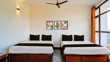 Ein Hotelzimmer mit zwei Betten, einem Deckenventilator und einem Fenster mit Vorhängen.