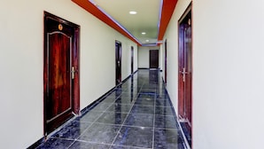 Un couloir avec des portes, un sol carrelé et un plafond doté d’un éclairage encastré.