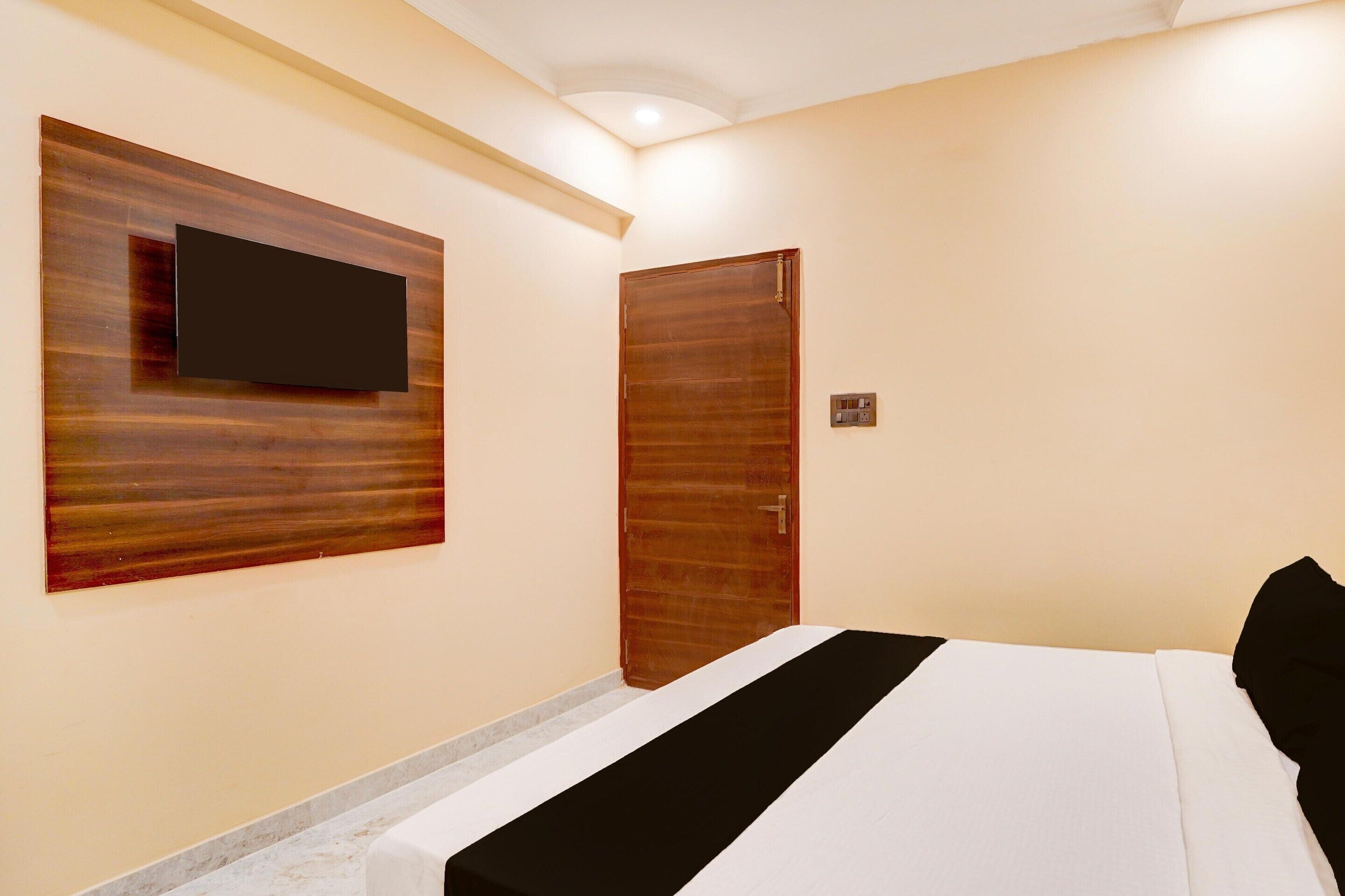 A hotel room with a bed, a television mounted on the wall, and a wooden door.