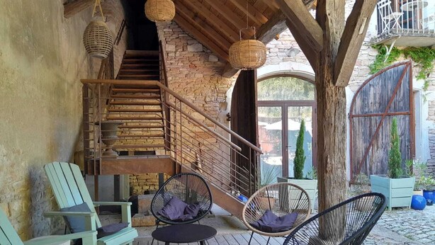 A wooden staircase leading to an upper level, wicker chairs, a small round table, and a stone wall. - Clos de Miribel-renovated former wine storehouse in the heart of Givry, quiet location for 15 people (Givry)