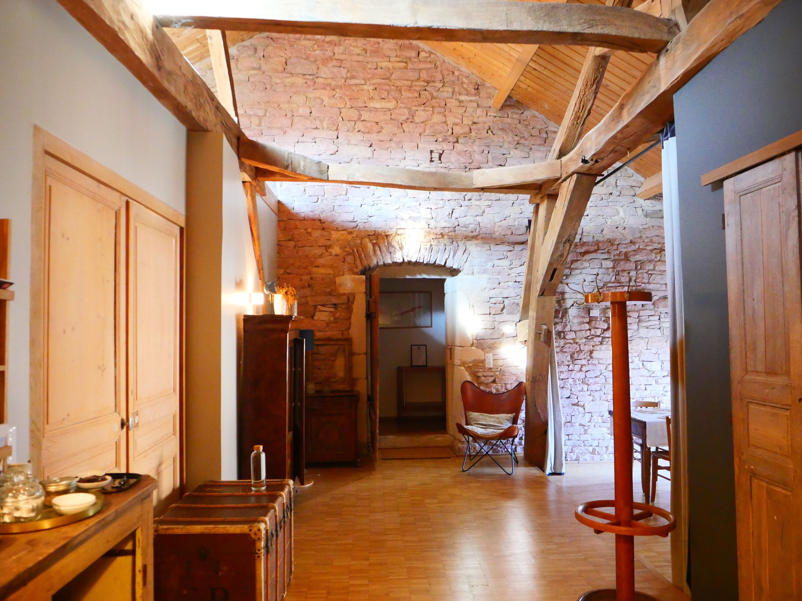 A rustic interior with exposed wooden beams, a stone wall, and a wooden floor.