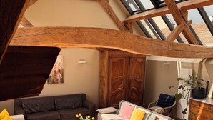 A loft-style living room with exposed wooden beams, a skylight, and a mix of sofas and chairs. - Clos de Miribel-renovated former wine storehouse in the heart of Givry, quiet location for 15 people (Givry)