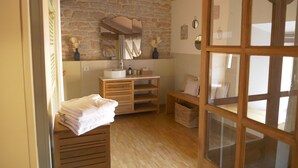 A rustic bathroom with a stone wall, wooden vanity, and a large mirror. - Clos de Miribel-renovated former wine storehouse in the heart of Givry, quiet location for 15 people (Givry)