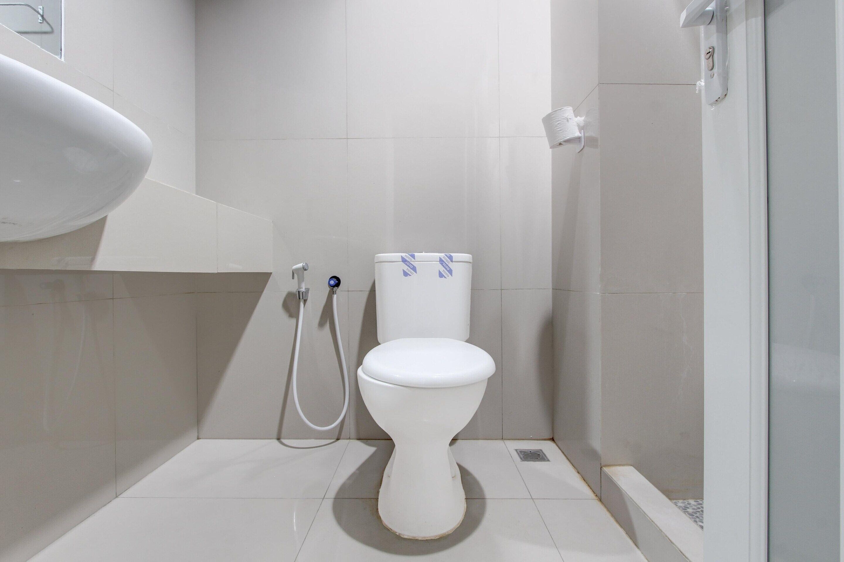 Un baño moderno con inodoro blanco, zona de ducha y lavabo.