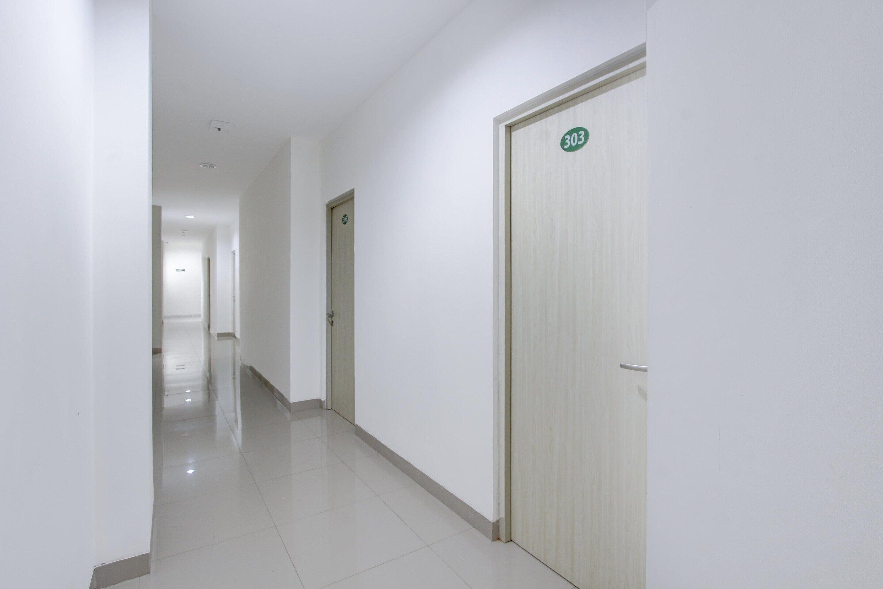 Un couloir avec une porte portant le numéro « 303 » et un autre couloir menant à une autre pièce.