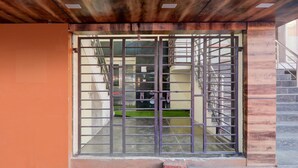 A metal gate with a view of a staircase and a building in the background. - Super Deluxe Room Skd Hotel and Banquet (Bakshi Ka Talab)