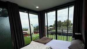 Un dormitorio con dos camas, ventanas amplias y vistas a un paisaje verde.
