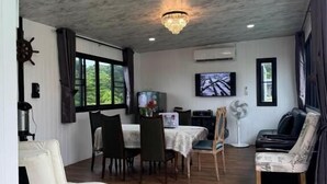 Un comedor con mesa y sillas, una araña, un televisor y vistas a zonas verdes.