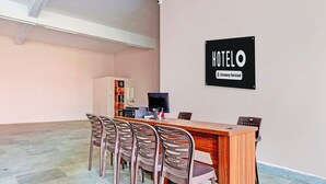 A hotel reception area with a wooden desk, six chairs, a television, and a sign indicating it is company-serviced.