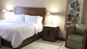 A bedroom with a bed, bedside tables, a chair, a rug, and a wall art piece. - Saint Martin Dawn Beach Club 2027 (SINT MARTEEN)
