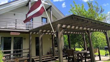 A building with a flag, outdoor seating, and a garden.