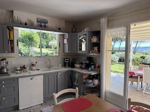 A kitchen with a dishwasher, a sink, and a window overlooking a garden. - Aix en Provence, near, beautiful country house 200 m2 with independent studio and swimming pool (VENTABREN)