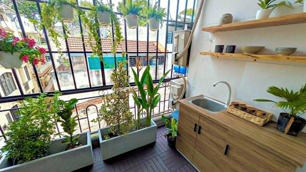 Een balkon met bloempotten, een houten kastje en uitzicht op de straat.