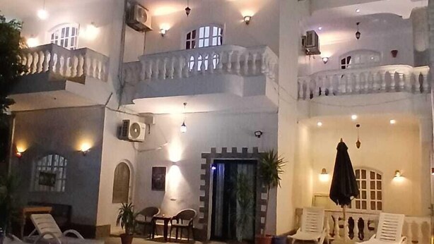 Un hotel a più piani con piscina, area salotto all'aperto e balconi.