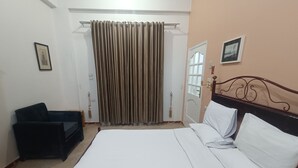 Una camera da letto con un letto, una sedia, una porta e una tenda.