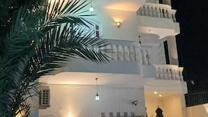 Un edificio a più piani con balconi, piscina e area salotto all'aperto.